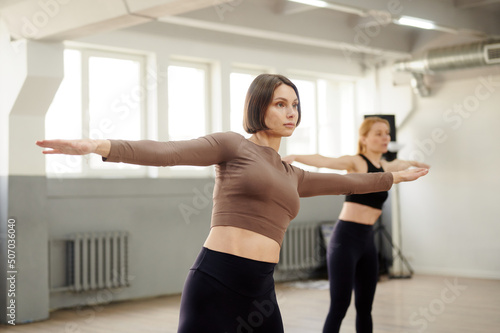 Group of young athletic women does a warm-up before training in the yoga hall. Stretching the body for a healthy lifestyle