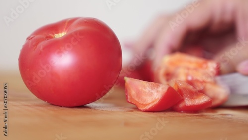 tomatoes are cut with a knife in the kitchen. healthy food salad vegetables concept. close-up lifestyle tomatoes in the kitchen hands close-up cut into slices