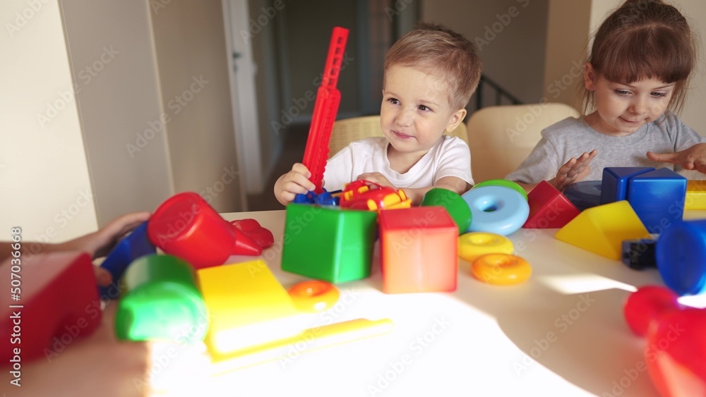 Obraz premium kindergarten. a group of children play toys cubes and cars on the table in kindergarten. kid dream creative happy family preschool education concept. nursery baby toddler lifestyle home