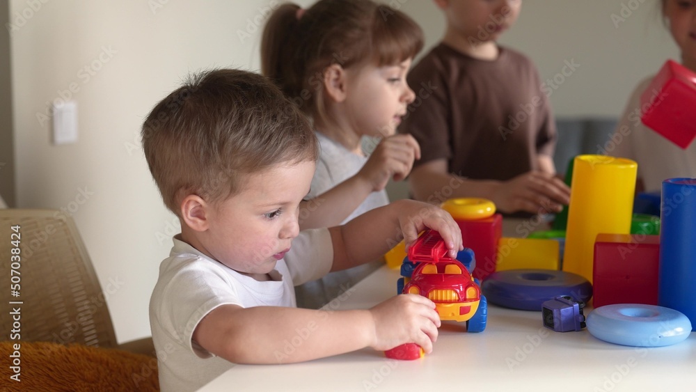 kids girl and baby boy play in kindergarten. a group of children play toys cubes and cars on the table in kindergarten. happy family preschool education concept. nursery baby indoor toddler home kids girl and baby boy play in kindergarten. a group of children play toys cubes and cars on the table in kindergarten. happy family preschool education concept. nursery baby indoor toddler home
