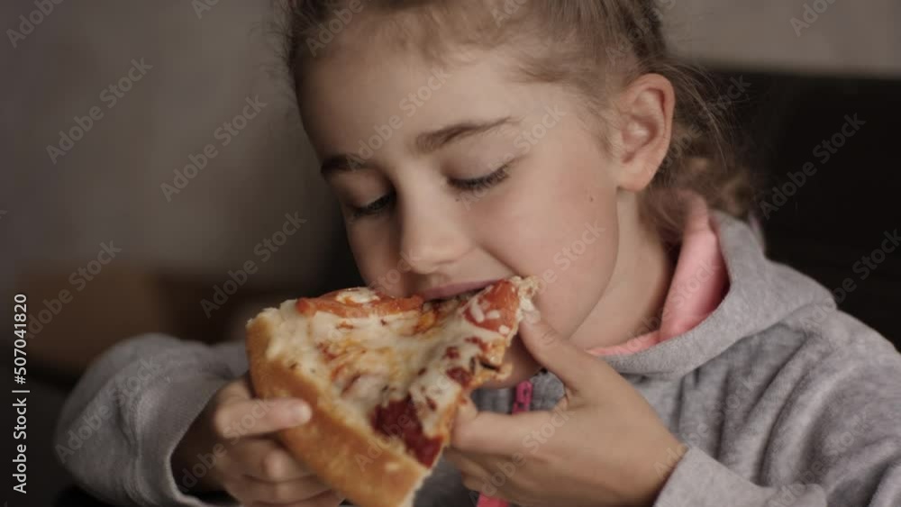 Unhealthy Nutrition Fast Food. Portrait of Kid Eating Lunch. Face Young Little Girl Closeup. Child Eat Pizza. Little Hungry Girl Eating Tasty Italian Pizza From Plate Sitting Home at Table in Kitchen. Unhealthy Nutrition Fast Food. Portrait of Kid Eating Lunch. Face Young Little Girl Closeup. Child Eat Pizza. Little Hungry Girl Eating Tasty Italian Pizza From Plate Sitting Home at Table in Kitchen.