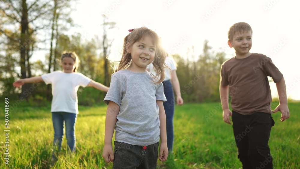 Fototapeta premium group of children in the park portrait. happy family baby kid dream concept. kindergarten. children play on green grass in sun forest park in summer sunlight