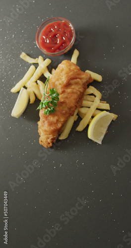 Vertical image of fresh homemade fried fish and chips on grey background