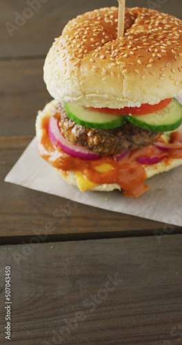 Vertical image of fresh homemade hamburger with salad on wooden background