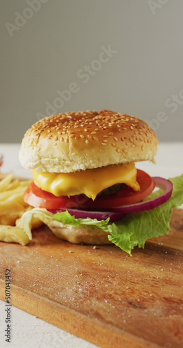 Vertical image of fresh homemade hamburger with salad on wooden chopping board