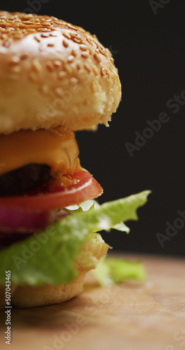 Vertical image of close up of fresh homemade hamburger with salad on grey background