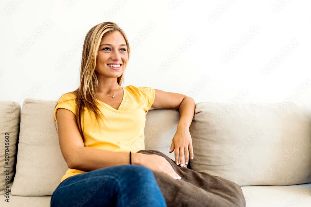 Portrait of a smiling young woman relaxing on the sofa at home. Cropped shot of attractive young woman wearing casual clothes while resting on sofa at home. Portrait of a smiling young woman relaxing on the sofa at home. Cropped shot of attractive young woman wearing casual clothes while resting on sofa at home.