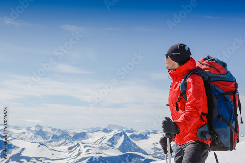 Hiker with backpack standing on top of a mountain and enjoying tne view photo