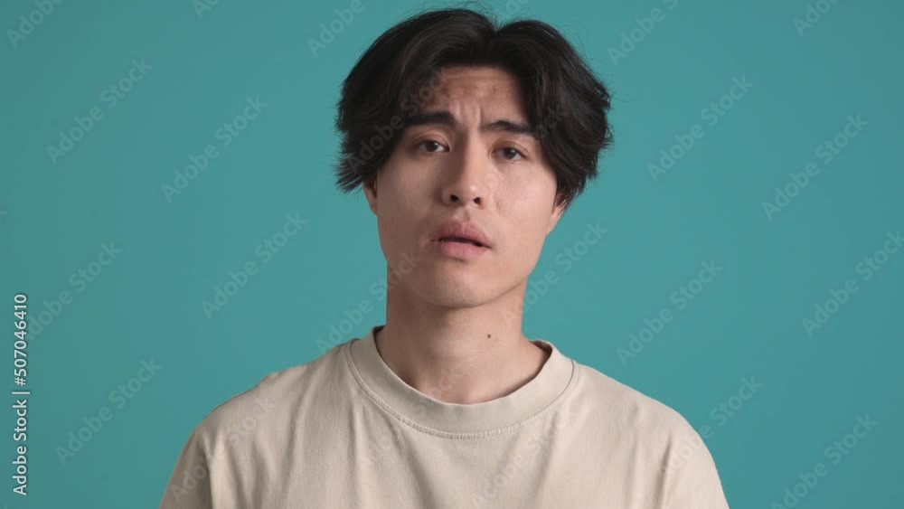 Handsome Asian brunet man thinking about something in the blue studio Handsome Asian brunet man thinking about something in the blue studio