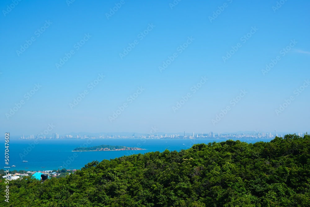Beautiful viewpoints of Koh Larn island, bright blue skyline, deep turquoise shade of sea water, green tree mountain and cityscape around bay. Landmark and travel destination of Pattaya thailand.