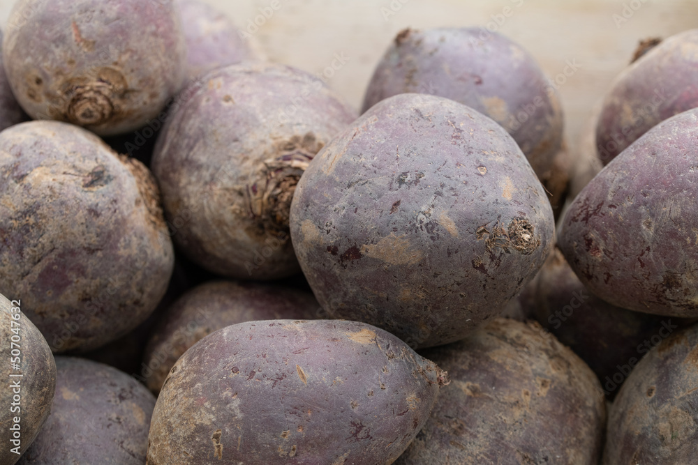 Several fresh beetroot bulbs with the skin on, lie side by side for sale in a crate Several fresh beetroot bulbs with the skin on, lie side by side for sale in a crate
