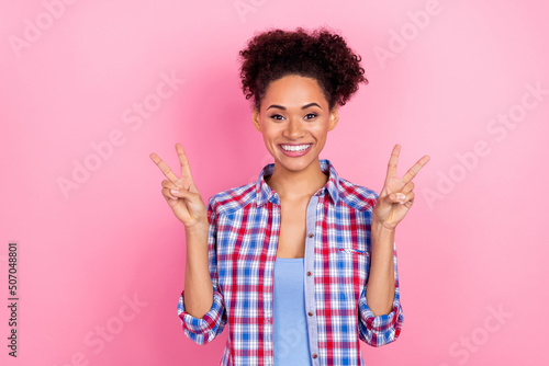 Photo of cool young curly hairdo lady show v-sign wear blue shirt isolated on pink color background