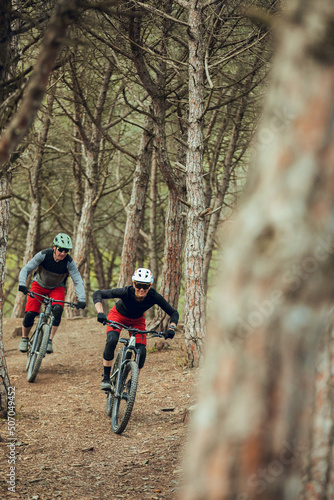 Couple of enduro mtb riders, woman and man going down the mtb trail in the forest of Barcelona