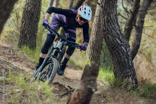 Close up of Woman mtb rider with australian shepherd dog riding mtb bike down trail in forest