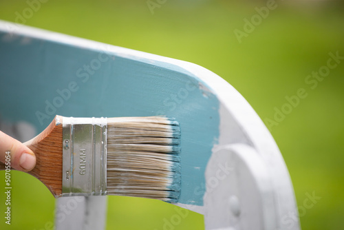 Close up paintbrush in hand and painting on the wooden furiture photo