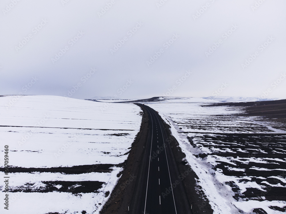 Aerial view of a road with one lane and snow in winter Aerial view of a road with one lane and snow in winter