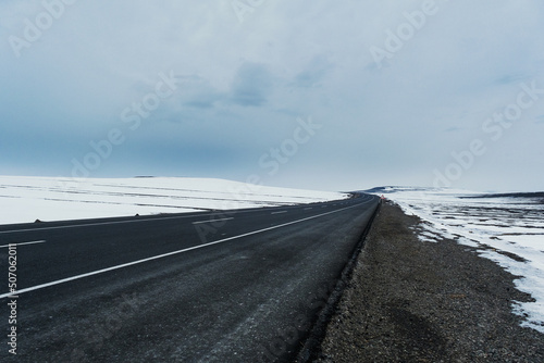 Diagonal view of an emtpy asphalt and bending road with lanes and snow in winter photo