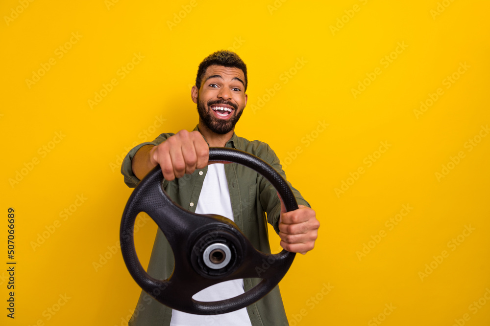 Photo of cute funky guy dressed green shirt riding auto empty space isolated yellow color background Photo of cute funky guy dressed green shirt riding auto empty space isolated yellow color background