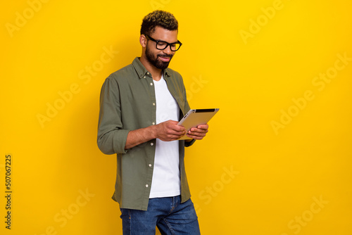Photo of pretty confident guy dressed green shirt eyewear chatting modern gadget isolated yellow color background