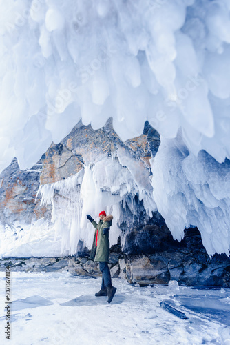 Woman traveler in red hat background of frozen grotto and pure ice winter Lake Baikal