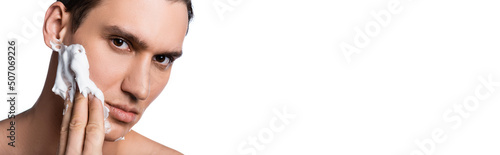 portrait of man applying shaving foam and looking at camera isolated on white, banner. photo