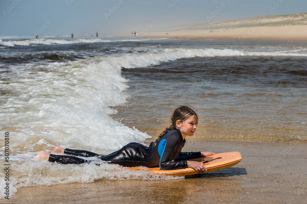 pretty little girl enjoying surfing the waves with a bodyboard during her vacation pretty little girl enjoying surfing the waves with a bodyboard during her vacation