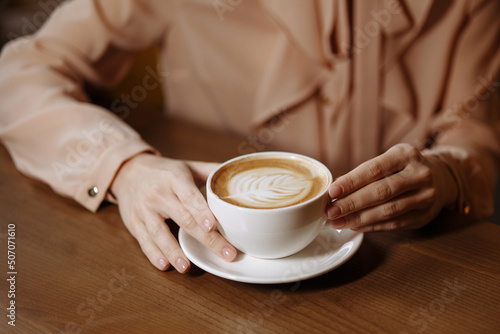 A womans hands hold a cup of coffee