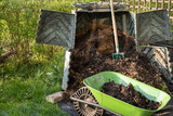 Ready made compost soil in wheelbarrow for next use. Plastic composter bin and digged compost