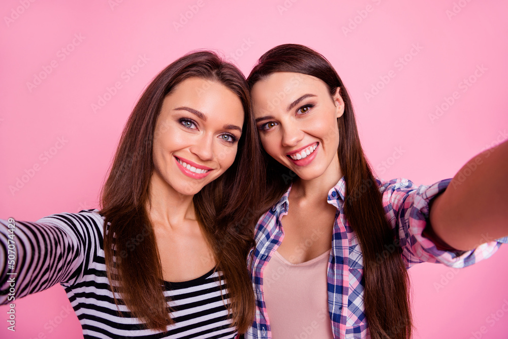 Photo of two charming cheerful girls make selfie record video toothy smile isolated on pink color background Photo of two charming cheerful girls make selfie record video toothy smile isolated on pink color background