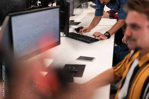 Group of Casual business man working on desktop computer in modern open plan startup office interior. Selective focus 