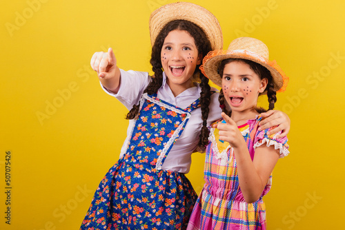 sisters and friends, wearing typical clothes of the Festa Junina. pointing to the horizon, look there. photo