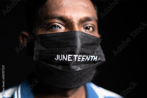 Print op canvas Close up shot of man with juneteenth medical face mask looking at camera during