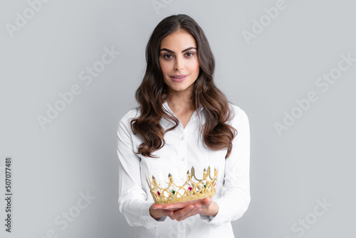 Woman queen. Portrait of ambitious girl with crown, feeling princess, confidence. Studio shot isolated on gray background.