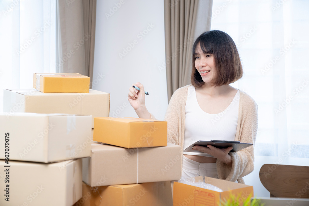 Young Asian female counting purchase order parcel before sending to customer from home Young Asian female counting purchase order parcel before sending to customer from home