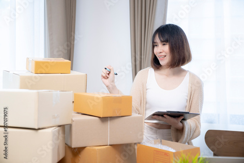 Young Asian female counting purchase order parcel before sending to customer from home