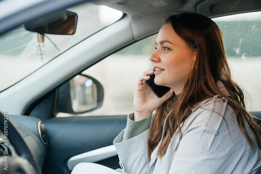 beautiful girl with long hair in a grey trench coat using smartphone call gets into the car beautiful girl with long hair in a grey trench coat using smartphone call gets into the car