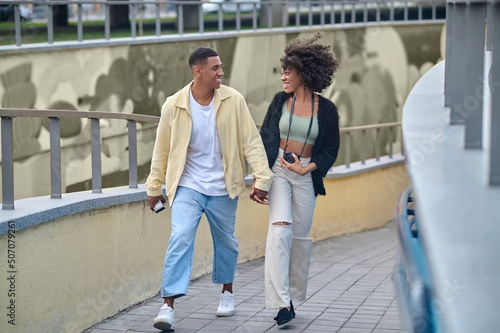 Happy guy and girl walking hand in hand