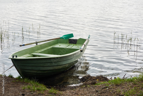 Small green boat anchored in forest lake. Scandinavia. Transportation, traditional craft, recreation, leisure activity, healthy lifestyle, local tourism, sport, rowing, hiking, summer vacations themes photo