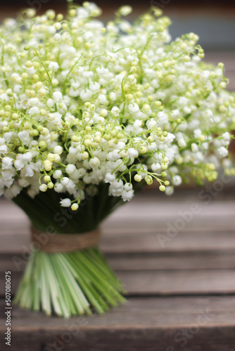 white lush bouquet of lilies of the valley on wooden steps