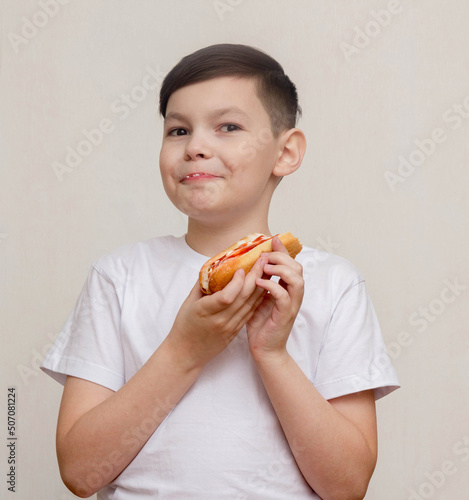 Little boy eats a huge hot-dog sandwich
