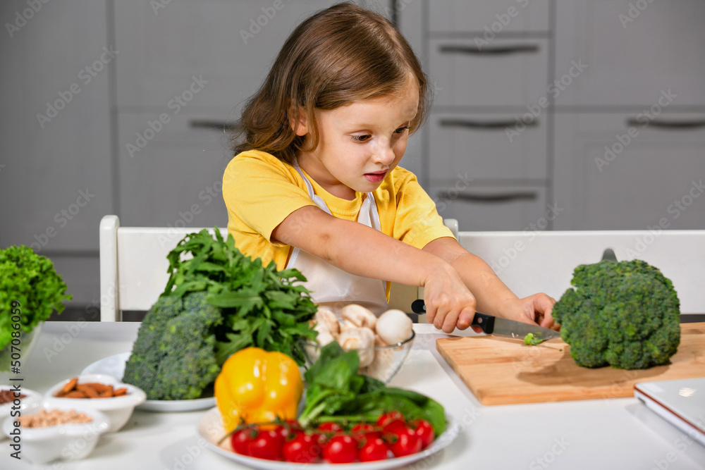 A child cook prepares healthy food with raw fresh greens.