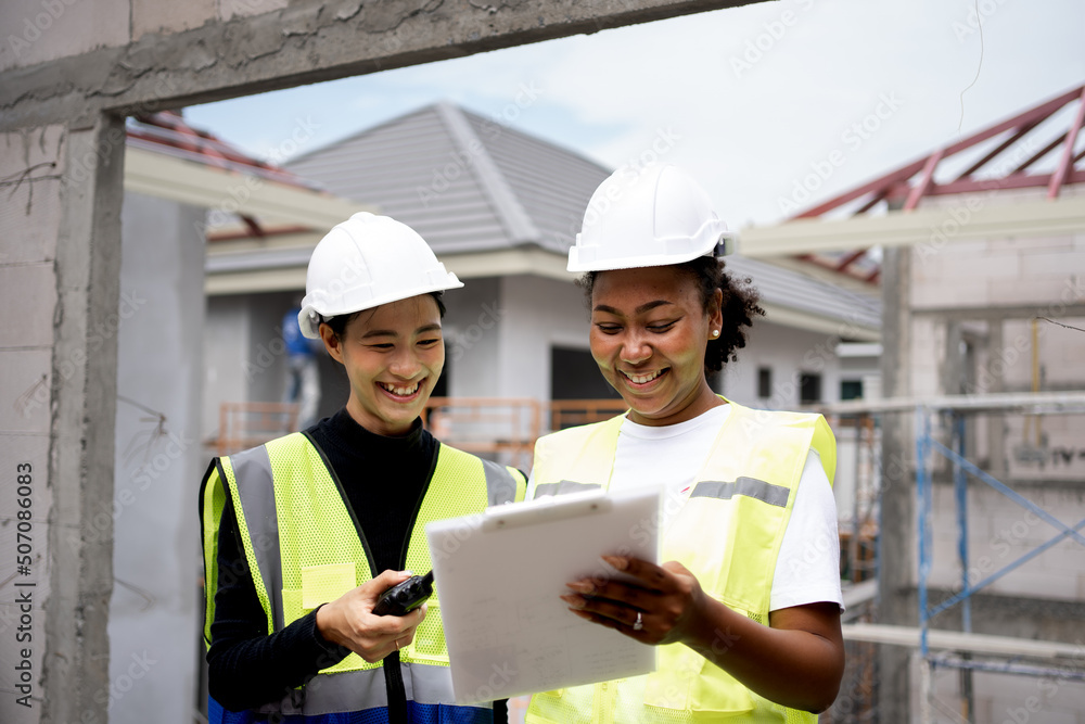 Team of beautiful female engineers inspecting the quality of house construction. Multi-ethnic group of Africans and non-Americans.female holding clipboard.ppe wearing safety firse concept. Team of beautiful female engineers inspecting the quality of house construction. Multi-ethnic group of Africans and non-Americans.female holding clipboard.ppe wearing safety firse concept.