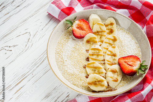 sweet porridge with quinoa and banana on a white rustic wooden background photo
