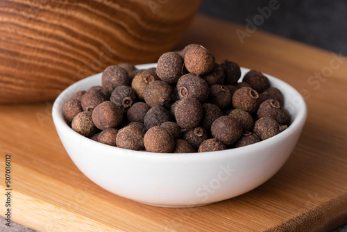 Pile of allspice isolated. Jamaica pepper, allspice peppercorns or myrtle pepper in a wooden spoon.