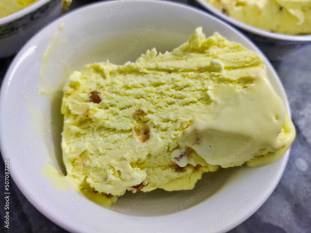 Picture of ice-cream being cut in slices with a knife for serving shot in a kitchen in indoors during summers