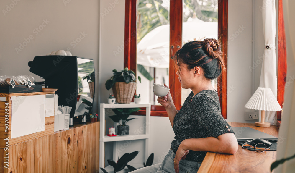 Beautiful Asian woman sits down at the bar counter inside a window ...