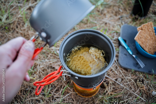 Wallpaper Mural Tourist utensils, camp cooking in a pot, open the lid look inside the pot, cook noodles, a quick meal in nature, lunch in the forest on the grass, trekking in the mountains Torontodigital.ca