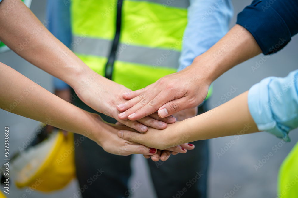 Group of engineers and workers join hands for teamwork in warehouse factory Group of engineers and workers join hands for teamwork in warehouse factory