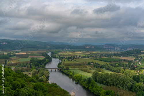 view of the picturesque Dordogne Valley with river and bridge in dense green summer forest
