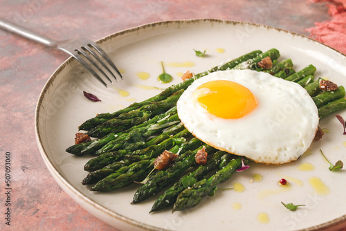 grilled asparagus, with fried egg, spices and herbs, parmesan cheese, on a beige plate, top view, rustic, no people